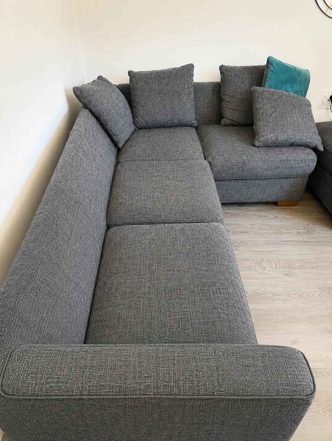 The same grey corner sofa after cleaning, photographed from the other end, the seat colour even throughout