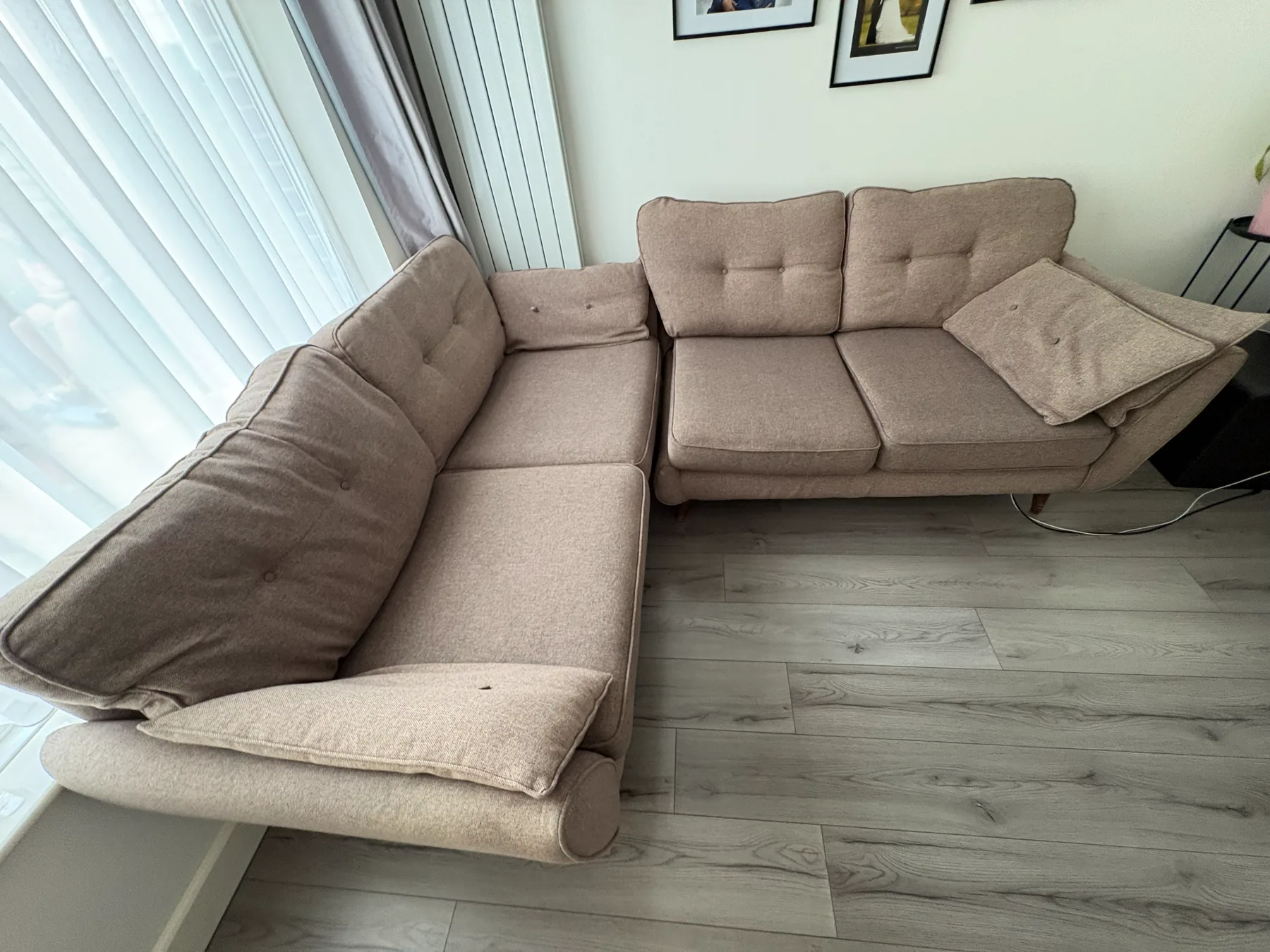 A pale oatmeal corner sofa in a bright living room, cushions back in place after cleaning